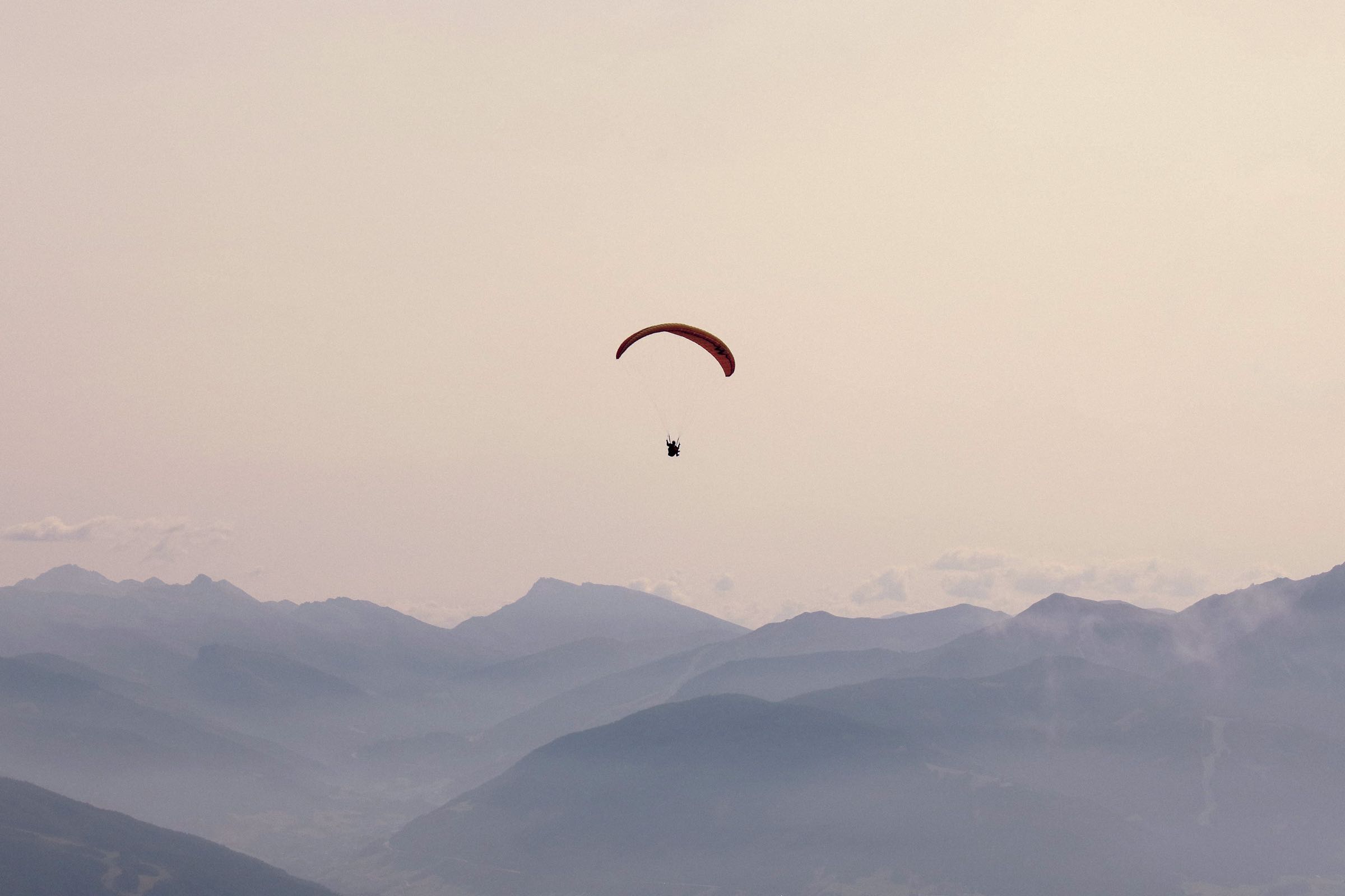 Gleitschirmflieger über nebligen Bergketten
